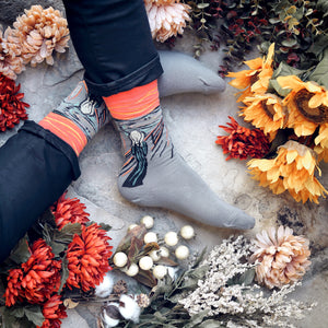 Close-up shot of a pair of grey The Scream socks with coral-toned accents.