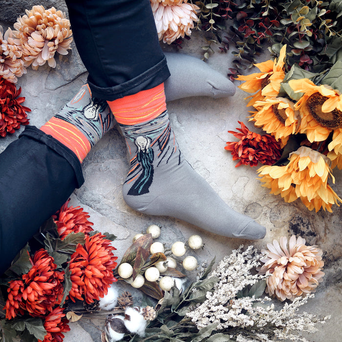 Close-up shot of a pair of grey The Scream socks with coral-toned accents.
