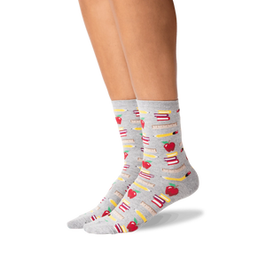 Lifestyle photo showing the socks on a person's legs; they are grey with a school supplies pattern.