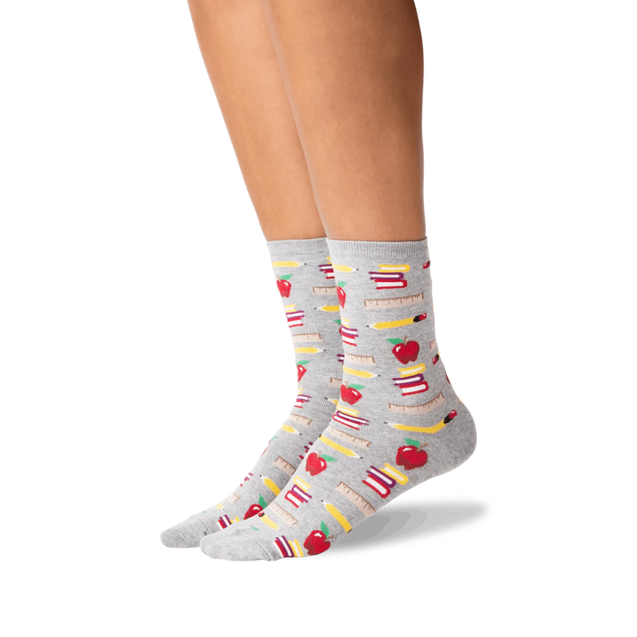 Lifestyle photo showing the socks on a person's legs; they are grey with a school supplies pattern.