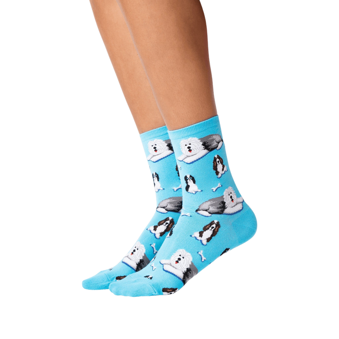 A pair of blue socks with a pattern of cartoonish black and white dogs wearing Santa hats.