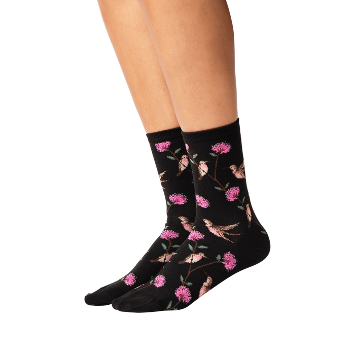 Lifestyle shot of woman's legs wearing black crew socks with hummingbird pattern.