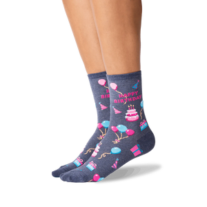 Lifestyle shot showcasing a woman's legs wearing the dark grey 'Happy Birthday' crew socks. The socks' design is clearly visible.