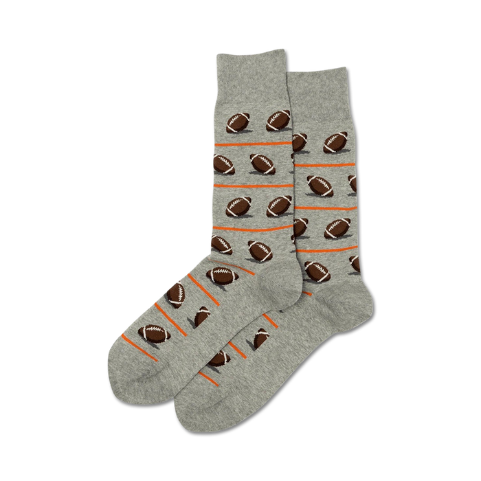 A pair of gray crew socks with a pattern of brown footballs and orange stripes.