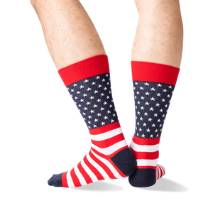 Rear view of the American Flag socks on a person's legs against a green background. The socks are red, white, and navy.