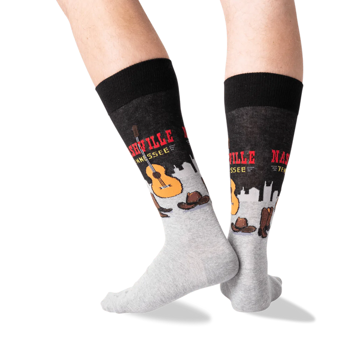 A pair of gray socks with a black top. The socks have a pattern of guitars, cowboy hats, and the words 