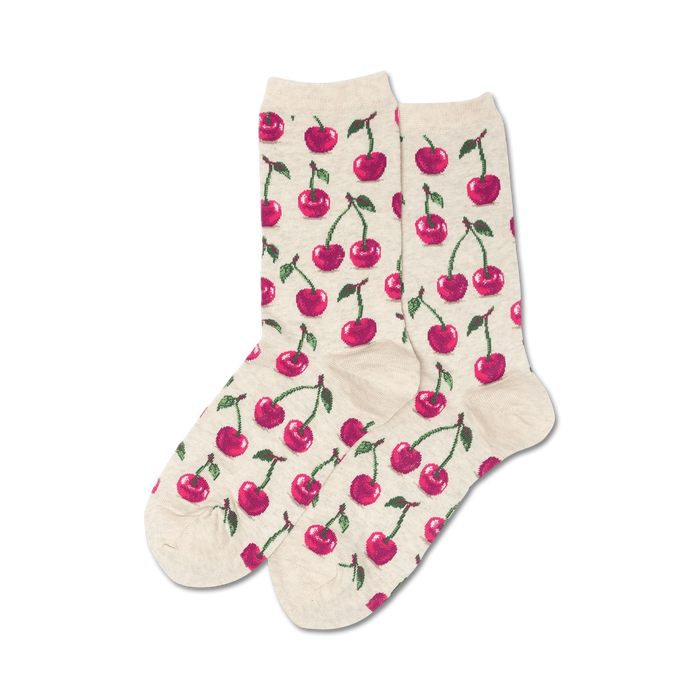 Lifestyle flatlay image showing a pair of beige crew socks with a red cherry pattern.