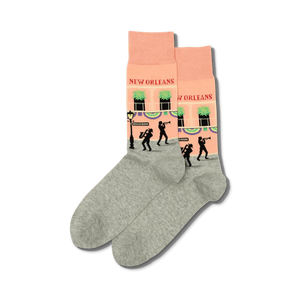 Pair of crew socks in peach and grey.  The peach section features a New Orleans street scene with jazz musicians and buildings.