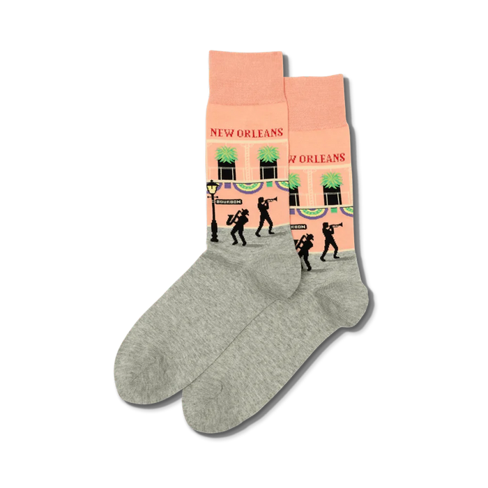 Pair of crew socks in peach and grey.  The peach section features a New Orleans street scene with jazz musicians and buildings.