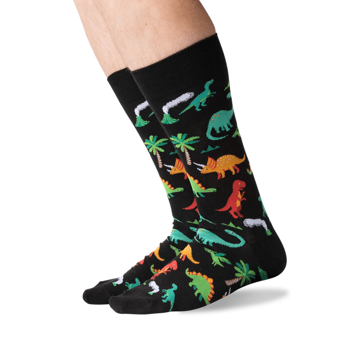 Lifestyle shot showing the dinosaur socks on a person's legs against a green background.
