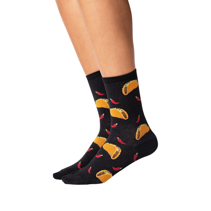 Lifestyle shot showing the socks on a person's legs. They're black with a taco and chili pepper pattern.