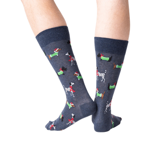 Back view of a person's legs wearing dark gray Christmas dog socks against a black background.