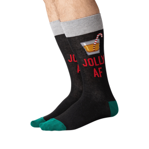 Flat lay of a pair of 'Jolly AF' socks. They are black with green cuffs.
