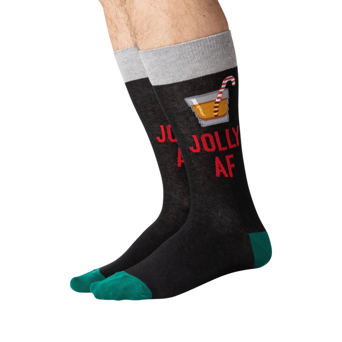 Flat lay of a pair of 'Jolly AF' socks. They are black with green cuffs.