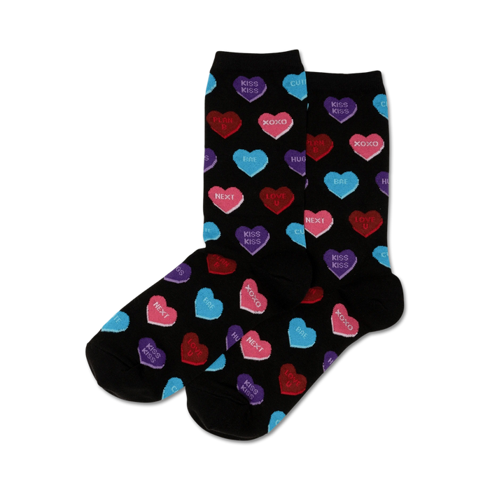 Pair of women's crew socks. Black background with colorful candy hearts that say 'Kiss Kiss', 'XOXO', etc.