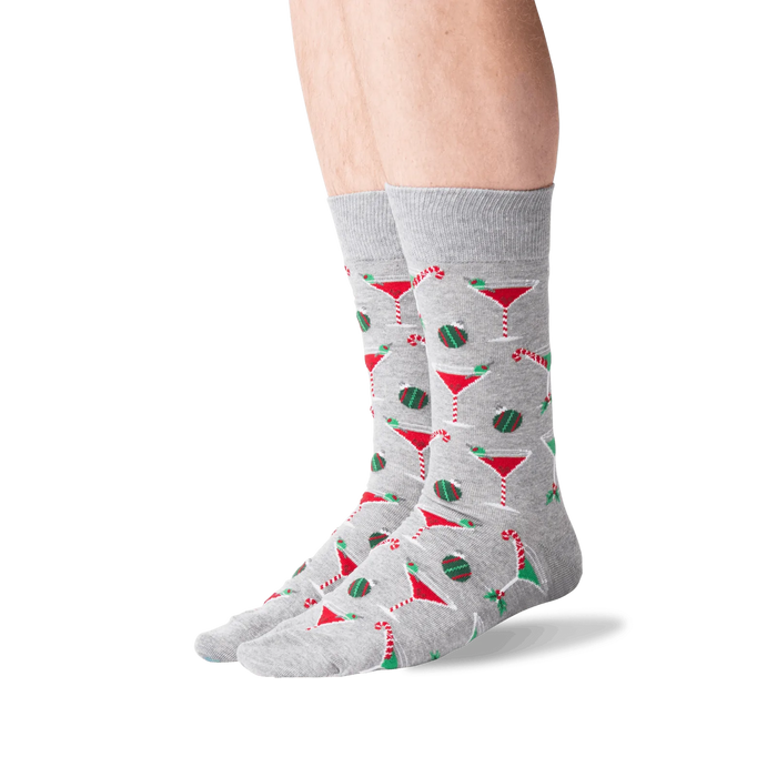 A pair of gray socks with a pattern of red and green martini glasses, candy canes, and ornaments.
