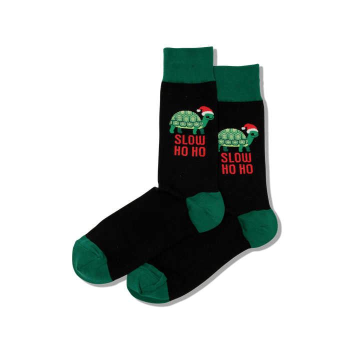 Pair of black crew socks with dark green cuffs, heels, and toes. Features green turtles wearing Santa hats and
