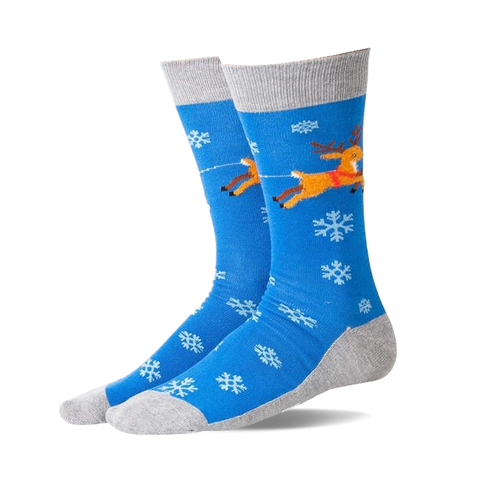 Pair of blue non-skid slipper socks with flying brown reindeer, red harness, white snowflakes, and grey cuffs, heels, toes. }}