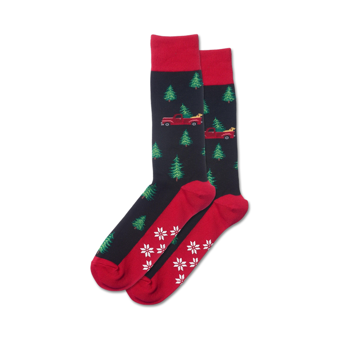 black crew socks with red pickup trucks hauling green christmas trees, red cuffs and toes with white snowflakes, non-skid grippers on red soles.   