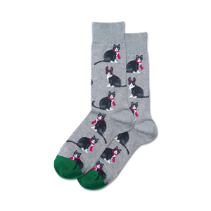 Pair of crew socks; gray background with repeating pattern of black tuxedo cats wearing red scarves and reindeer antlers; green cuffs.