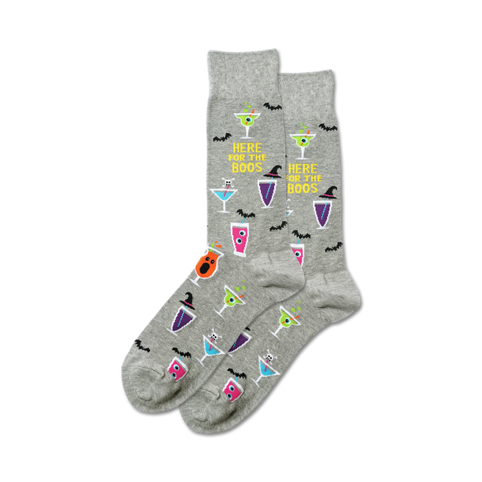 A pair of grey crew socks with a Halloween theme. The socks feature colorful cocktail designs, bats, and the text 'Here For The Boos'. }}