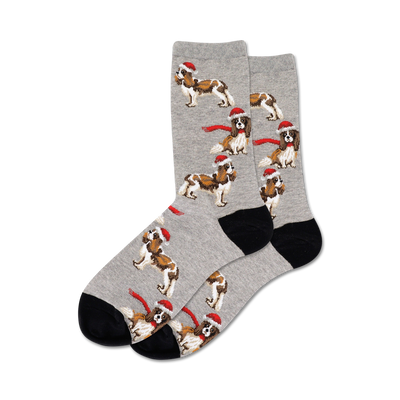 Pair of crew socks in grey with a pattern of Cavalier King Charles Spaniels wearing Santa hats and red scarves. Black heel and toe.