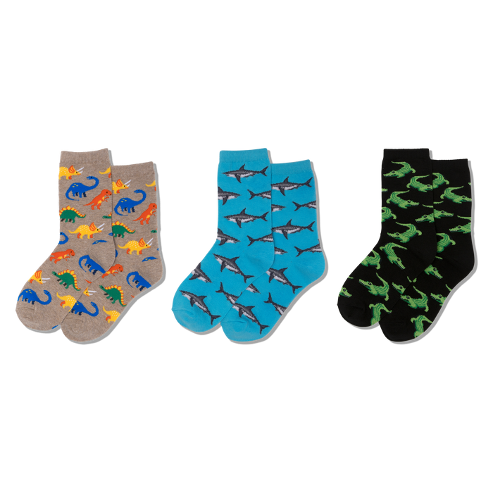 Three pairs of crew socks: one tan with colorful dinosaurs, one blue with grey sharks, and one black with green crocodiles. }}