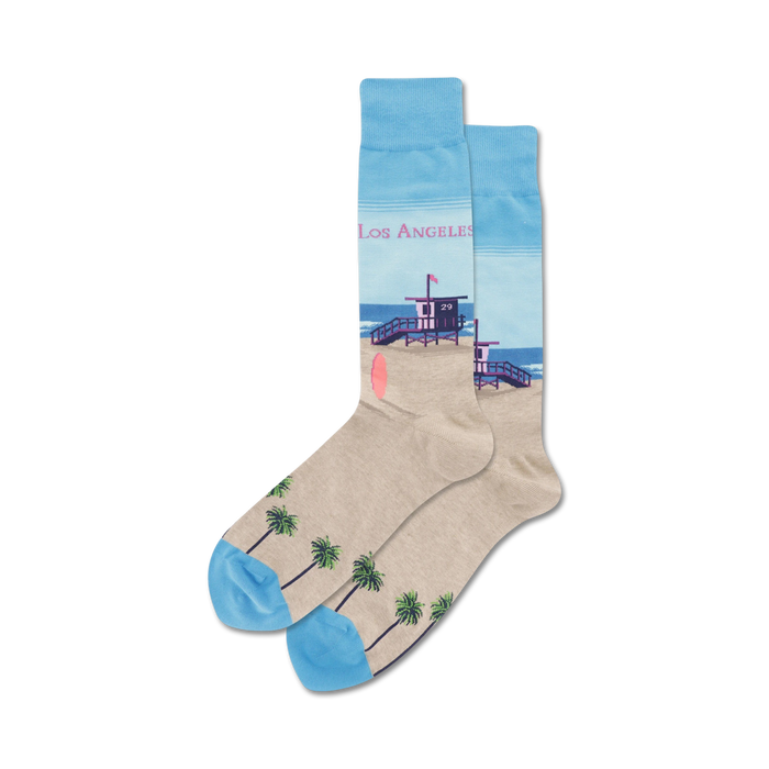 Pair of crew socks showcasing a beach scene: light beige with palm trees at the bottom, a lifeguard tower, and a light blue ocean. 'Los Angeles' text is subtly included. }}