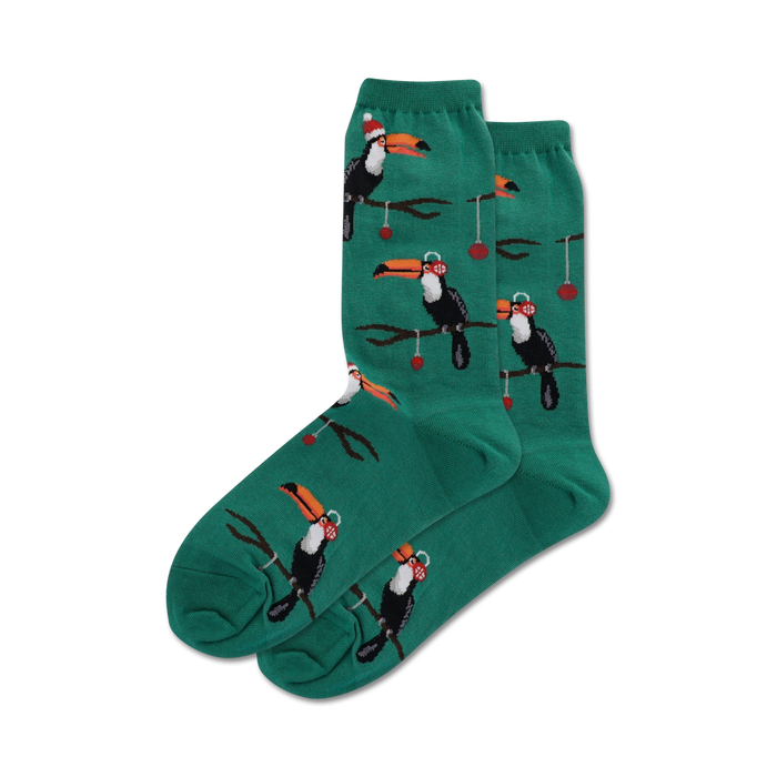 Pair of teal crew socks with a repeating pattern of toucans wearing Santa hats and ornaments hanging from branches. }}
