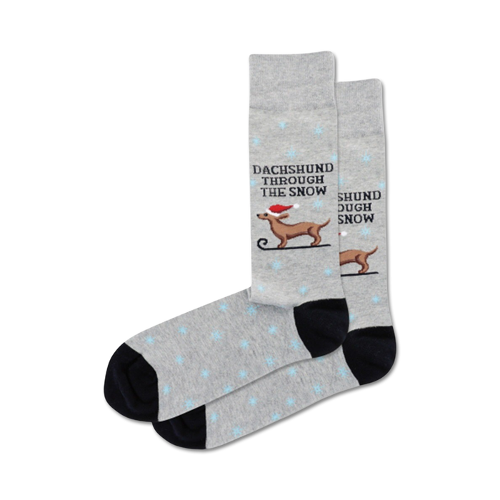 Pair of grey crew socks with a black cuff. Features a dachshund in a Santa hat sledding, snowflakes, and the text 'Dachshund Through the Snow'.
