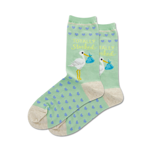 Pair of women's crew socks in mint green with a stork design, tiny hearts, and the text 'Totally Storked'.