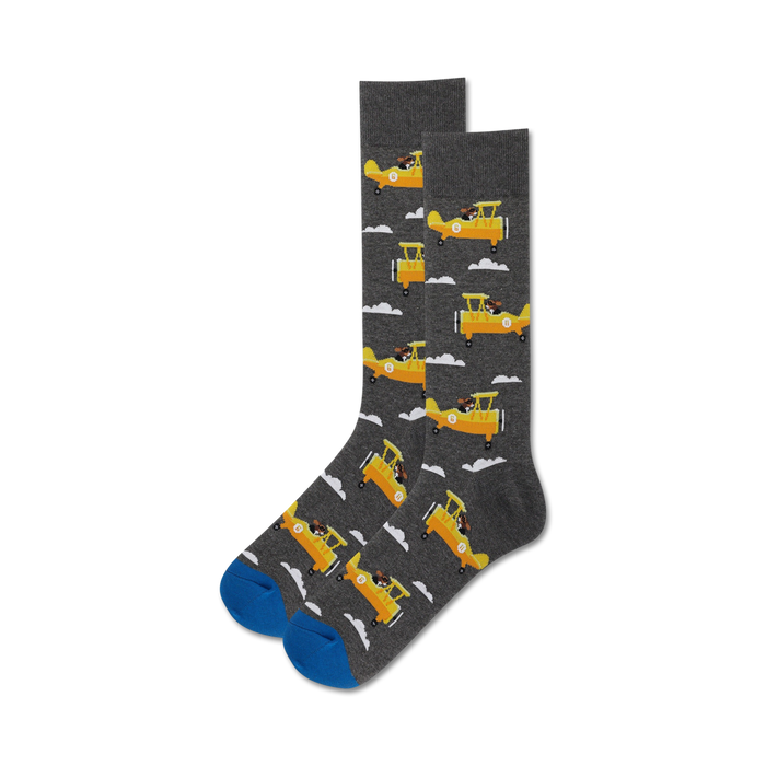 Close-up of a pair of gray crew socks with yellow airplanes and dogs; blue sole.
