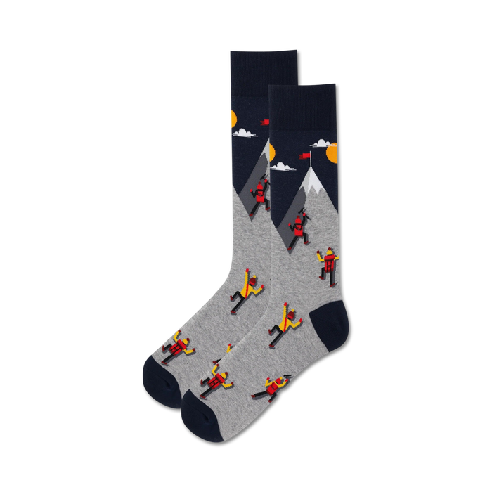 Pair of grey and navy crew socks. Design features cartoon climbers ascending a mountain with a yellow sun and clouds. }}