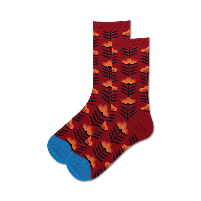 Lifestyle shot:  A pair of burgundy crew socks with an orange retro floral design are casually displayed.