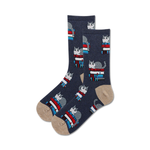 Close-up of dark blue crew socks with a tan cuff; featuring a pattern of grey cats on stacks of colorful books.