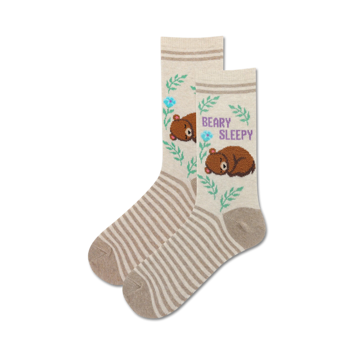 Pair of cream-colored fuzzy socks with brown sleeping bears, light blue flowers, and green leaves. Features thin brown stripes and 'Beary Sleepy' text. }}