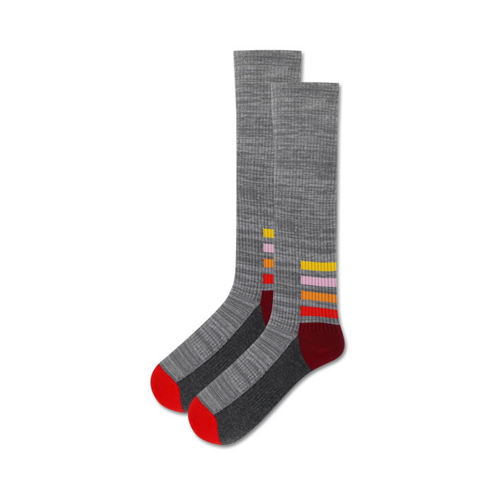 Pair of grey ankle socks with colorful horizontal stripes near the cuff. Red, orange, yellow, and pink stripes on a dark grey background. }}