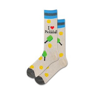 A close-up studio shot shows a pair of beige pickleball socks with teal stripes. The design includes paddles, balls, and the text 'I love Pickleball'.