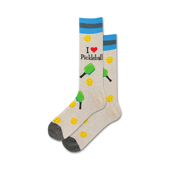 A close-up studio shot shows a pair of beige pickleball socks with teal stripes. The design includes paddles, balls, and the text 'I love Pickleball'.