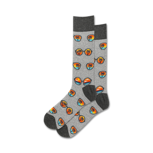 Pair of grey crew socks with a repeating pattern of retro sunglasses and palm trees at sunset. Orange, blue, and black design elements on a heather grey background.