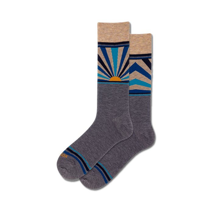 Pair of gray crew socks with a colorful sunrise design. The design includes shades of blue, beige, and orange, with geometric sun rays. }}