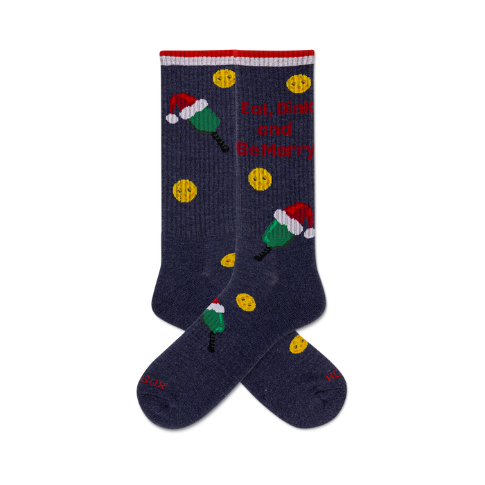 Pair of dark blue crew socks with a Christmas theme. Design includes yellow smiley faces, green and red popsicles wearing Santa hats, and the phrase 'Eat, Drink & Be Merry'. }}