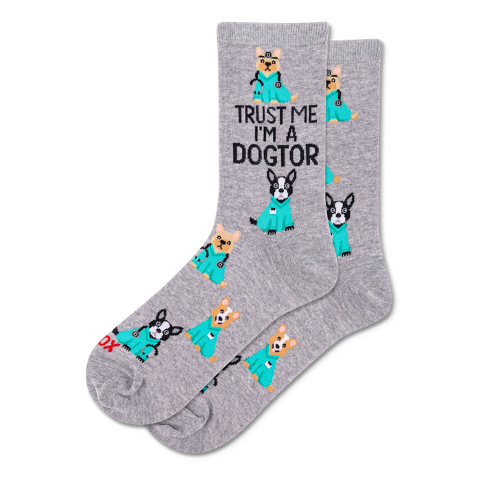 Pair of grey crew socks with a repeating pattern of cartoon dogs in teal medical scrubs, some with stethoscopes. Text reads