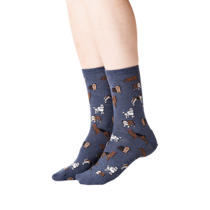 Lifestyle shot of woman's legs wearing navy blue crew socks with dogs on them.