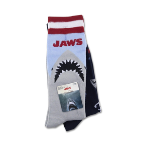 A pair of Jaws socks folded with the packaging. The socks are blue and gray with a red stripe at the top and feature the Jaws logo and a great white shark.
