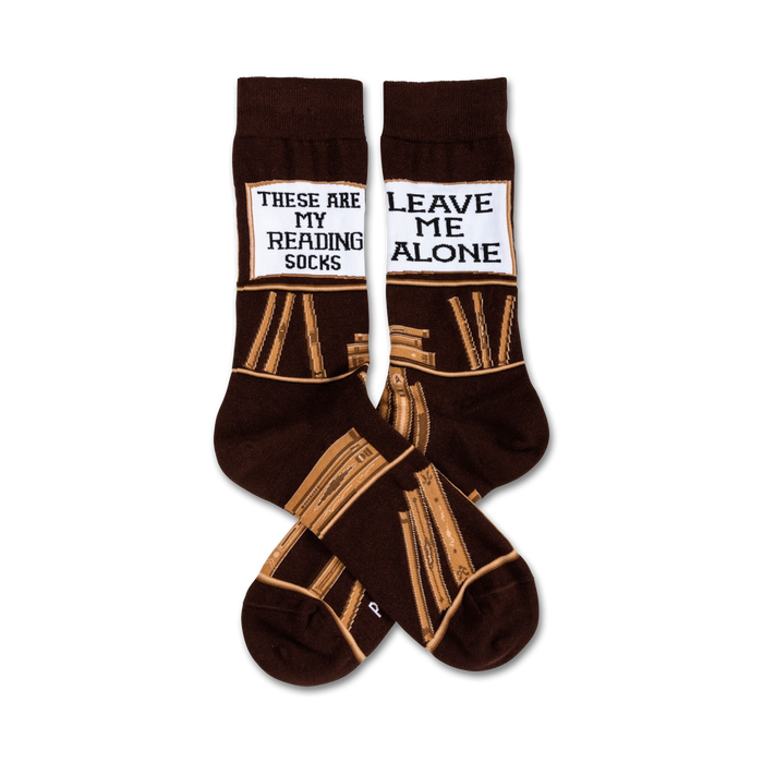 Pair of brown crew socks with a tan book stack design and a white label reading 'These Are My Reading Socks' and 'Leave Me Alone'. }}