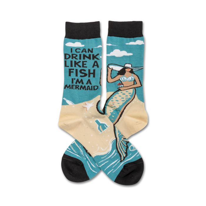 Crew socks showcasing a teal mermaid design on beige sand, with the text 'I can drink like a fish, I'm a mermaid'. }}
