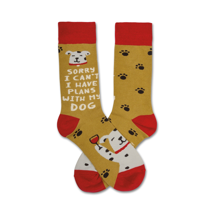 A pair of mustard yellow crew socks with red cuffs.  One sock shows a Dalmatian and 'Sorry I can't I have plans with my dog.' The other sock has paw prints. }}