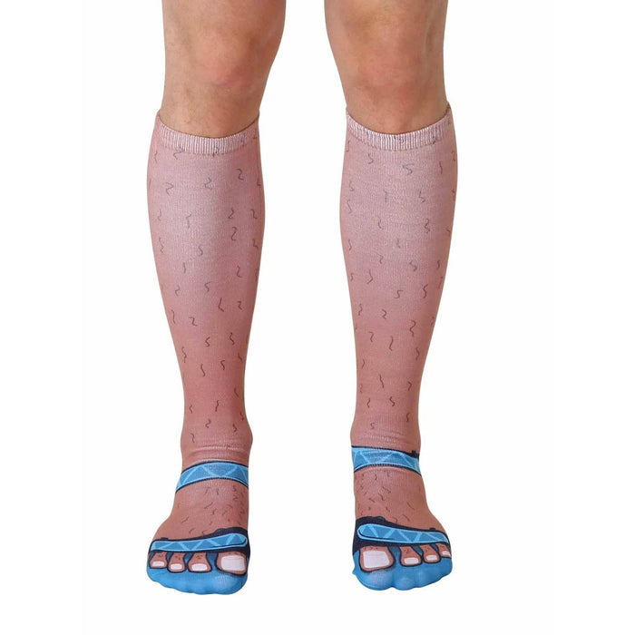 Pair of tan crew socks with printed hairy legs and blue sandals. Fun novelty socks for a quirky style statement.