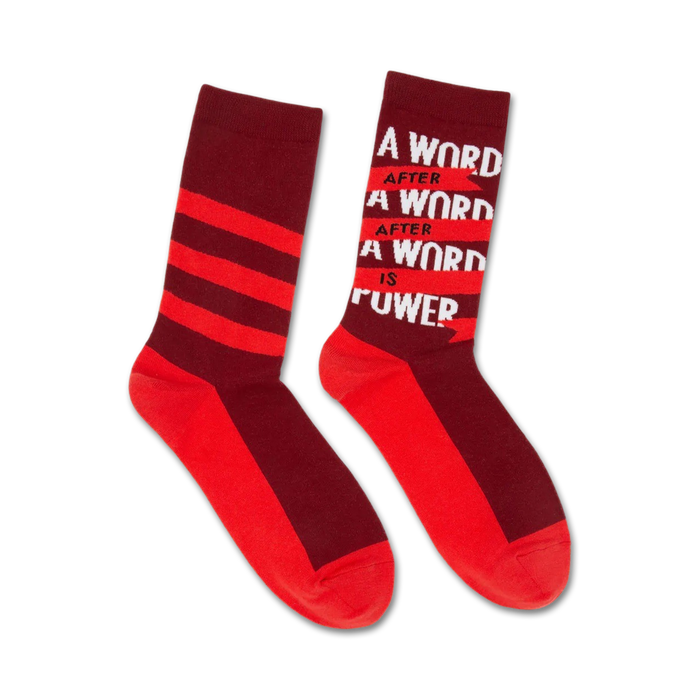 Pair of crew socks in red and burgundy. One sock features horizontal stripes, the other displays 'A word after a word after a word is power'. }}